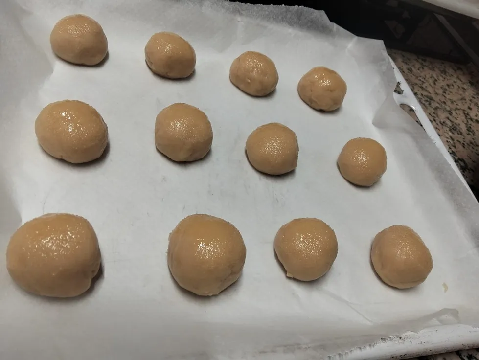 Preparación de la masa de kurabiiki en bolitas sobre papel vegetal antes de entrar al horno.